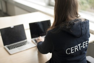 CERT-EE kirjaga pusaga naine tegemas tööd sülearvutis.